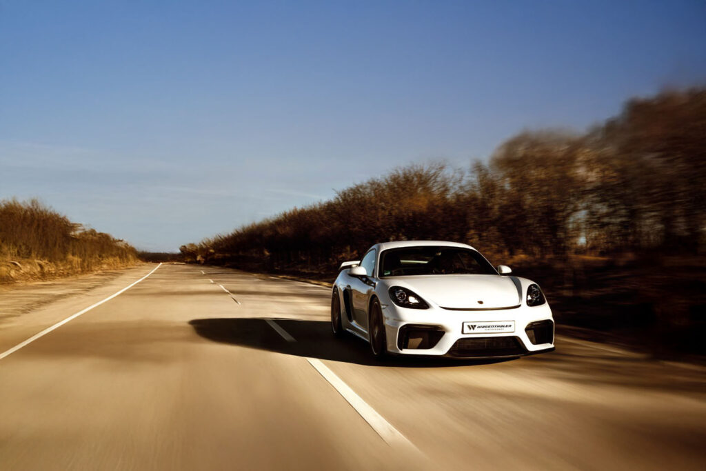 Porsche weiss faehrt schnell auf strasse im herbst