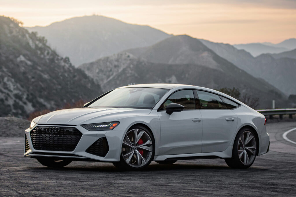 Weisser audi vor grauem sonnenuntergant auf passstrase fotografiert